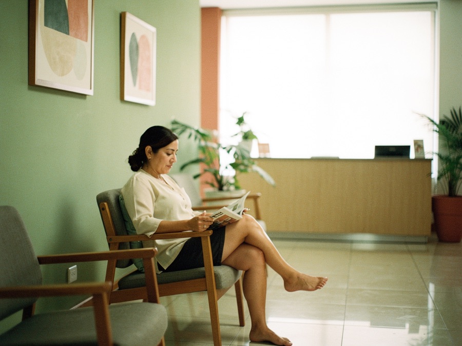 Una mujer espera tranquila, leyendo, en la sala de un consultorio luminoso